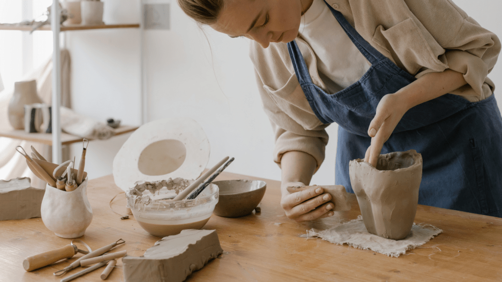 a woman in the process of sculpting using clay